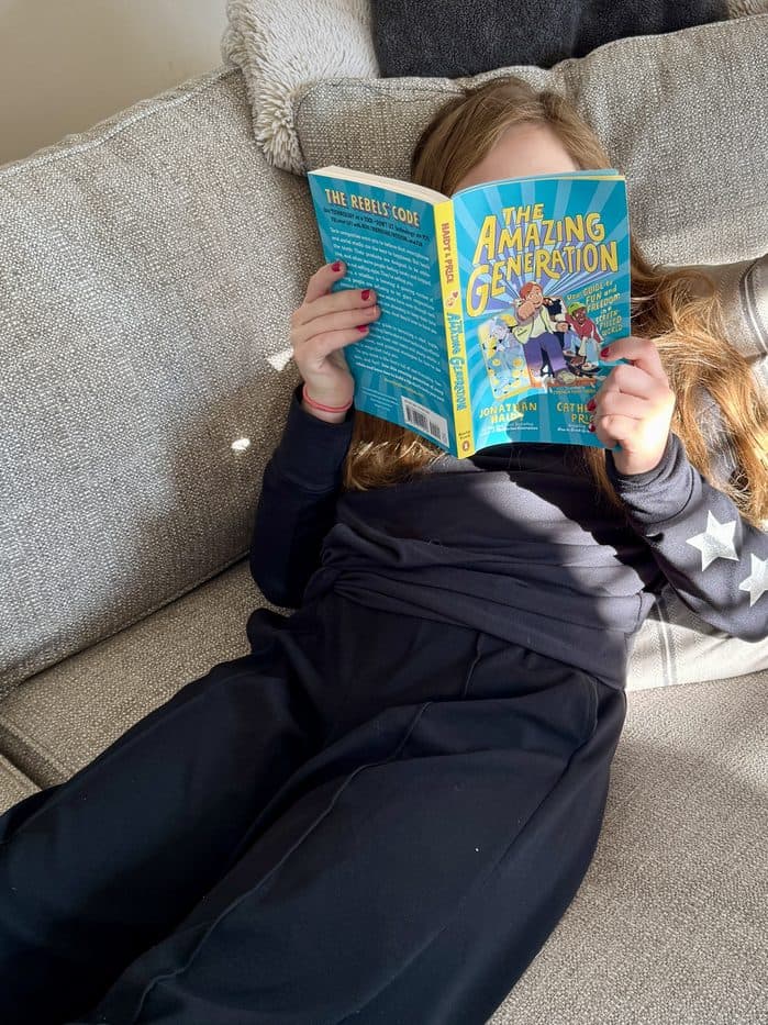 A girl stretched out on the couch, absorbed in a paperback chapter book