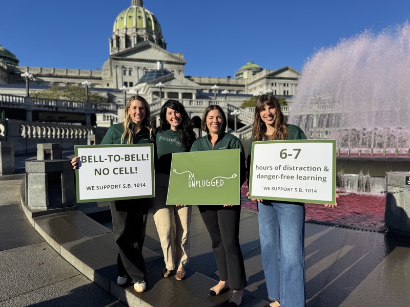 Four PA Unplugged co-founders with signs at the Capitol fountain in Harrisburg